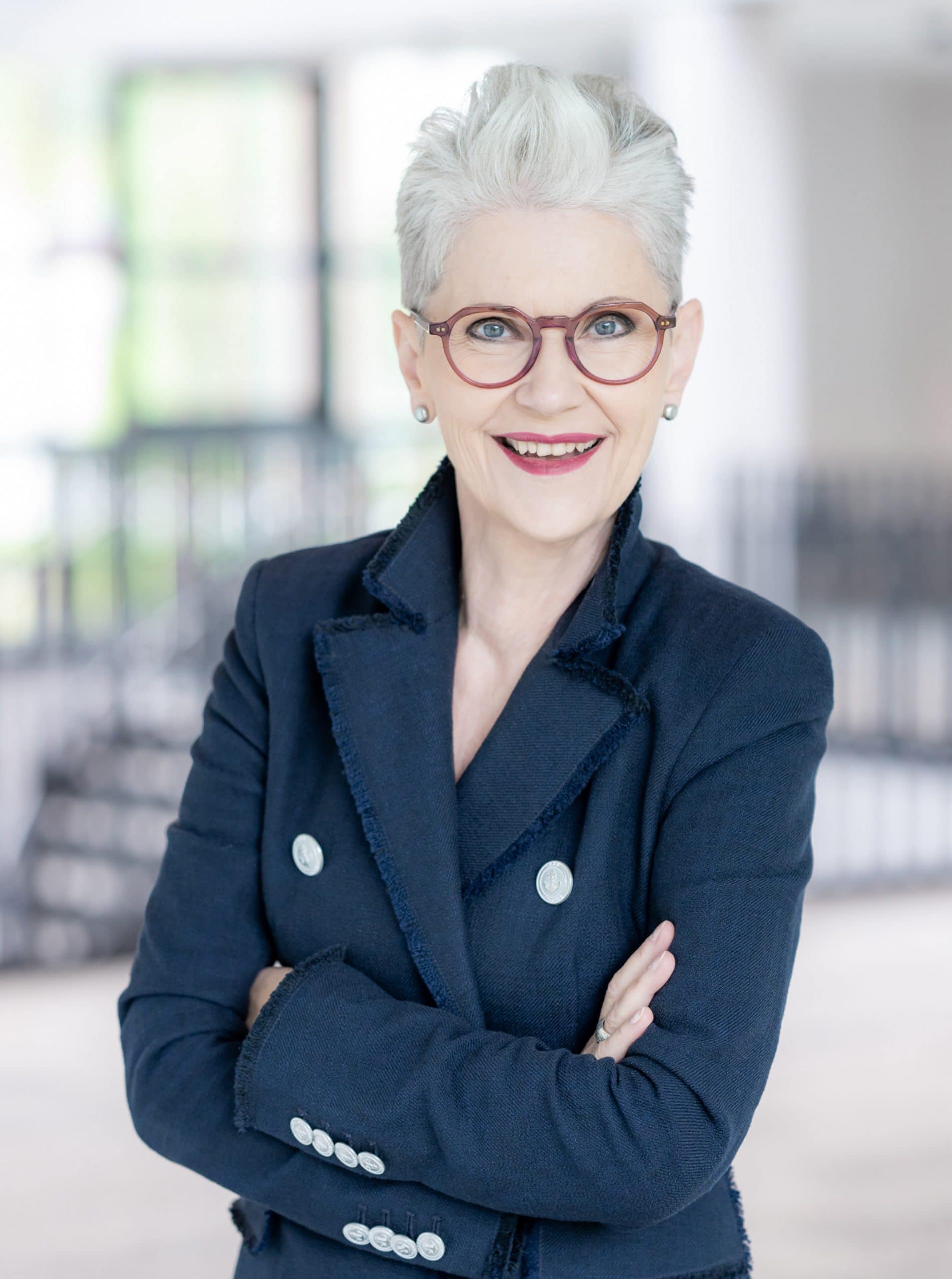 Das ist Elisabeth Motsch, sie ist bei einem Fotoshooting mit dem Tiroler Goldschmied in Meran. Sie hat weißes Haar, trägt eine weiße Bluse, dazu sehr schönen Schmuck in Weißgold mit Steinen in einem außergewöhnlichen Design.
