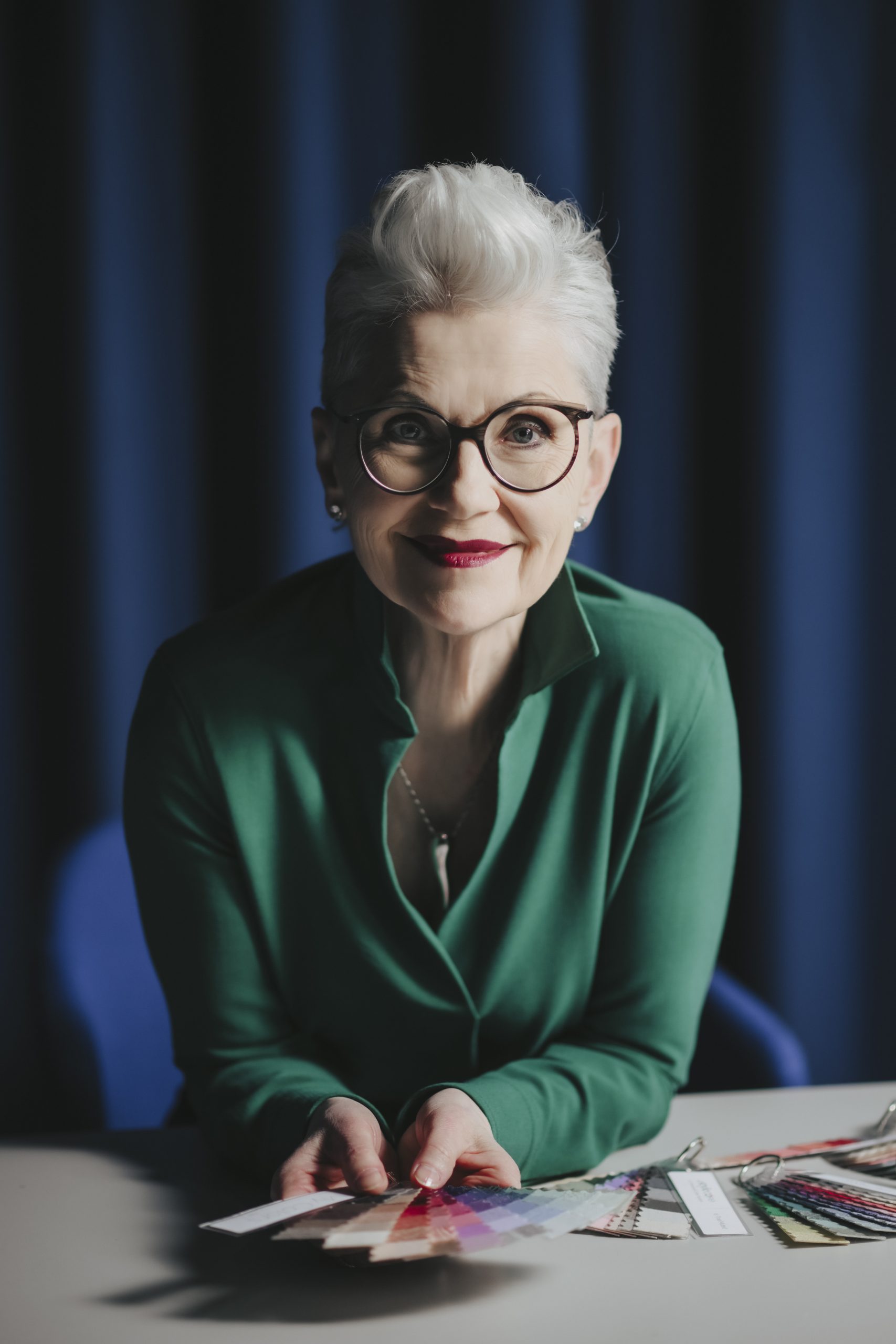Das ist Elisabeth Motsch, sie ist bei einem Fotoshooting mit dem Tiroler Goldschmied in Meran. Sie hat weißes Haar, trägt eine weiße Bluse, dazu sehr schönen Schmuck in Weißgold mit Steinen in einem außergewöhnlichen Design.